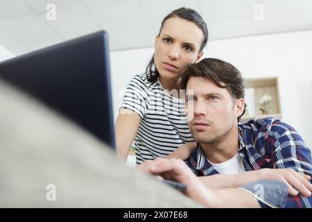 Konzentriertes, besorgtes Paar, das sich ein Notebook anschaut Stockfoto