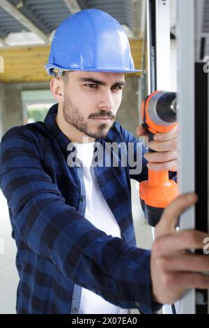 Der Mann bohrt ein Loch in den Schrank Stockfoto