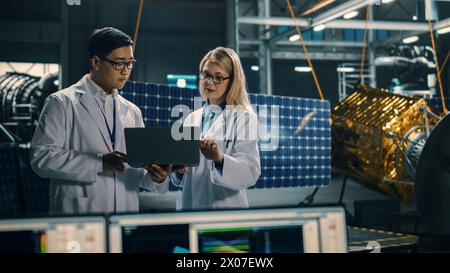 Ingenieur und Techniker, die an der Satellitenkonstruktion arbeiten. Luft- und Raumfahrtbehörde: Ein Team von Wissenschaftlern, die technologische Ausrüstung und Laptop-Computer nutzen, um Raumfahrzeuge für die Weltraumforschung zu entwickeln. Stockfoto