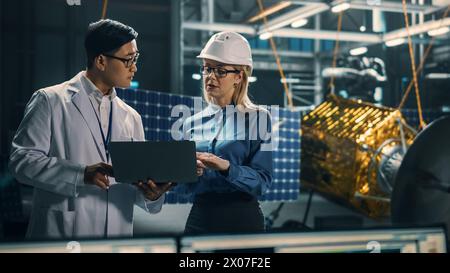 Ingenieur und Techniker, die an der Satellitenkonstruktion arbeiten. Luft- und Raumfahrtbehörde: Ein Team von Wissenschaftlern, die technologische Ausrüstung und Laptop-Computer nutzen, um Raumfahrzeuge für die Weltraumforschung zu entwickeln. Stockfoto