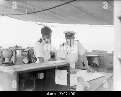 DIE MEERE WIEDER SICHER MACHEN. 1945. AUGUST AUF SEE IM GOLF VON GENUA. MIT DER 12. MINENRÄUMUNGSFLOTTE IM GOLF VON GENUA UNTER DEM KOMMANDO VON COMMANDER C SIMPSON, DSC, RN, COMMANDER MINENRÄUMUNG WESTITALIENS. SIE ARBEITEN AUF DER GRUNDLAGE VON KAPITULIERTEN FEINDKARTEN UND WERDEN VON SUPERMARINE WALROSSEFLUGZEUGEN UND DER US NAVY-ABSCHOTTUNG ZUR MINENBEOBACHTUNG UNTERSTÜTZT. - Auf der Brücke von HM Minesweeper FLIEGEN Captain C W Rawlings, DSO und Bar, DSC, RN, von Salisbury, Wilts, leitender Offizier der Flottilla, plante eine Wiegeoperation mit seinem Navigator, Lieut A R B Sturdee, DSC, RN, aus London Stockfoto