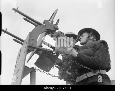 Eine Twin Hotchkiss Gun Crew auf dem Handelsschiff SS Scythia steht an den Aktionsstationen und bereitet sich darauf vor, während des Zweiten Weltkriegs auf ein feindliches Flugzeug zu schießen Stockfoto