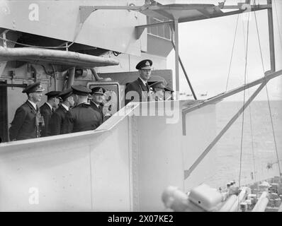 DER KÖNIG BESUCHT DIE HEIMATFLOTTE. 14. AUGUST 1943, SCAPA FLOW. DER KÖNIG BESUCHTE MÄNNER UND SCHIFFE DER HEIMATFLOTTE, ER GING AN BORD DES FLOTTENFÜHRERS HMS ONSLOW, DER IHN ZUM FLAGGSCHIFF HMS DUKE OF YORK BRACHTE. HIER TRAF DER KÖNIG AUF ADMIRAL SIR BRUCE A FRASER, KBE, CB, C-IN-C-FLOTTE. - Der König, mit C in C Admiral Sir Bruce Fraser und Offizieren des HERZOGS VON YORK, die Luftmanöver über die Flotte beobachten Stockfoto