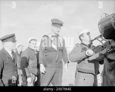 DEMS-SCHÜTZEN HALTEN PACE MIT DEN NEUESTEN KRIEGSWAFFEN. 11. UND 12. NOVEMBER 1943, DEMS RANGES, CARDIFF. DAS DEMS-TRAININGSZENTRUM, IN DEM DIE MÄNNER, DIE FEINDLICHE SEE- UND LUFTANGRIFFE AUF ALLIIERTE HANDELSSCHIFFE ABWEHREN, AUFFRISCHUNGSKURSE ABSOLVIEREN, UM PACE MIT IHREN NEUEN VERTEIDIGUNGSWAFFEN ZU VERSORGEN. - Ein Ausbilder des Petty Officer, der die Abschussfehler einer amerikanischen Marine korrigiert, während er eine Oerlikon-Waffe benutzt Stockfoto