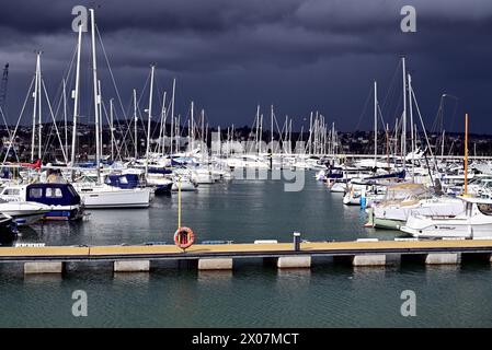 Sonnenschein und dunkle Wolken über Booten im Hafen von Torquay, wenn sich Regen nähert. Stockfoto