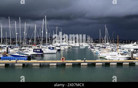 Sonnenschein und dunkle Wolken über Booten im Hafen von Torquay, wenn sich Regen nähert. Stockfoto