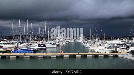 Sonnenschein und dunkle Wolken über Booten im Hafen von Torquay, wenn sich Regen nähert. Stockfoto