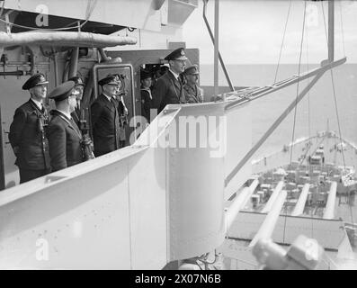 DER KÖNIG BESUCHT DIE HEIMATFLOTTE. 14. AUGUST 1943, SCAPA FLOW. DER KÖNIG BESUCHTE MÄNNER UND SCHIFFE DER HEIMATFLOTTE, ER GING AN BORD DES FLOTTENFÜHRERS HMS ONSLOW, DER IHN ZUM FLAGGSCHIFF HMS DUKE OF YORK BRACHTE. HIER TRAF DER KÖNIG AUF ADMIRAL SIR BRUCE A FRASER, KBE, CB, C-IN-C-FLOTTE. - Der König, mit C in C Admiral Sir Bruce Fraser und Offizieren des HERZOGS VON YORK, die Luftmanöver über die Flotte beobachten Stockfoto