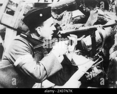 DER WARSCHAUER AUFSTAND, AUGUST-OKTOBER 1944: Ein Soldat der polnischen Heimatarmee, der ein deutsches Maschinengewehr MP40 hält, während er von der Barrikade aus auf den Feind wacht, August-September 1944. Beachten Sie ein weiß-rotes Armband am Soldatenarm, das als Äquivalent einer vollständigen polnischen Armee, polnischer Streitkräfte im Westen, Heimatarmee (Armia Krajowa) angesehen wurde. Stockfoto