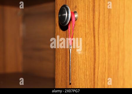 Eine Nähnadel hängt an einem Knopf. Stockfoto