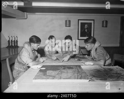 DIE ROYAL NAVY WÄHREND DES ZWEITEN WELTKRIEGS - Verhör der Grumman Avenger Bomberbesatzungen der 832 Squadron, Fleet Air Arm an Bord der HMS ILLUSTROUS. Von links nach rechts: Petty Officer R O Begley, Tail Gunner, aus Dulwich; Lieutenant G E Newton aus London, Verhörer; Sub Lieutenant (A) N D B Harris, Observer, aus Ewell, Surrey; und Sub Lieutenant (A) A W Stewart, Pilot, aus Dumbarton, Schottland. Zusammen mit amerikanischen, australischen, französischen und niederländischen Einheiten nahmen diese Männer an einem Luftangriff auf die japanische Held Marinebasis bei Surabaya Royal Navy, HMS illustrous, Flugzeugträger, (1939), Roya Teil Stockfoto