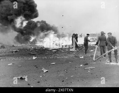 ROYAL AIR FORCE: AIR DEFENSE OF GREAT BRITAIN (ADGB), 1943-1944. - Feuerwehrleute sprühen Schaum über das Wrack einer brennenden de Havilland-Moskito in Predannack, Cornwall, nachdem sie Feuer über dem Flugplatz gefangen und nach einem Übungsflug aus 200 Metern abgestürzt war. Während die Feuerwehrleute das Flugzeug mit Schaum bedeckten, wurde versucht, die eingeschlossenen Flieger freizugeben, aber es wurde festgestellt, dass beim Absturz der Beobachter über den Piloten geworfen worden war und es schwierig war, bei übermäßiger Hitze an die Gurte zu gelangen (siehe CH 18732). Sie wurden schließlich von einem medizinischen Offizier freigeschnitten. Der Beobachter, der abfliegt Stockfoto