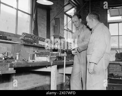 LEBEN IM ROYAL NAVY ARMAMENT DEPOT PRIDDY's HARD, GOSPORT, 25-30. JULI 1944 - in Th gunwharf von RNAD Priddy's Hard, Gosport, Einem Dobinson aus Gateshead-on-Tyne, Ex-Chief Armourer, der 22 Jahre in der Navy war (rechts), der Henry Baker aus Hastings zeigt, ein Trainee, wie man einen Colt .5 für Fleet Air Arm zusammenbaut, verwendet Royal Navy Stockfoto