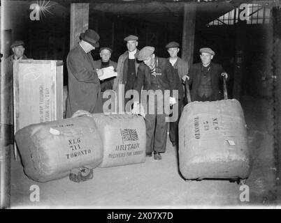 GROSSBRITANNIEN LIEFERT DIE WAREN IN KRIEGSZEITEN: HAFENARBEITER IN BRISTOL, ENGLAND, 1940 – Wollballen werden in einem Lagerhaus am Hafen in Bristol abgecheckt, bevor sie an Bord eines Schiffes für den Export nach Toronto, Kanada, gebracht werden Stockfoto