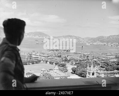 BRITISCHE KRIEGSSCHIFFE IM HAFEN VON HONGKONG. SEPTEMBER 1945. - Kriegsschiffe der britischen Marineeinheiten, die Hongkong vor Anker im Victoria Harbour wieder besetzt haben, auf dem Balkon des Gouverneurshauses. Silhouetted ist Sergeant J C Roswell aus Portsmouth Stockfoto