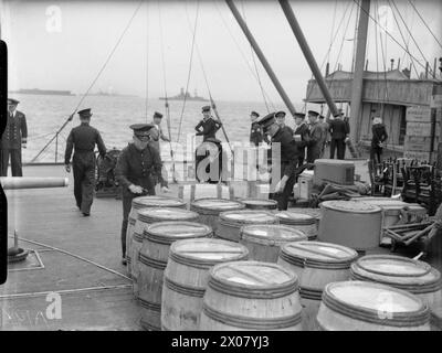 DIE ROYAL NAVY WÄHREND DES ZWEITEN WELTKRIEGS - Provisioning eines Kriegsschiffs der NELSON-Klasse, wahrscheinlich der HMS RODNEY, mit Vorräten für drei Monate. Royal Marines inspizieren die Läden, während sie an Bord gebracht werden. Die Fässer enthalten Geschirr. Die Brücke des Versorgungsschiffes ist im Hintergrund zu sehen. Das Schlachtschiff trug eine Besatzung von über 1300 Royal Navy, RODNEY (HMS) Stockfoto