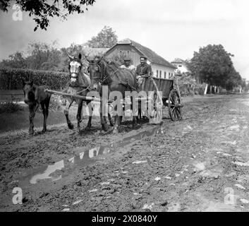 Die Sozialistische Republik Rumänien in den 1970er Jahren Männer, die einen Pferdewagen auf einer unbefestigten, matschigen Straße eines Dorfes reiten. Stockfoto