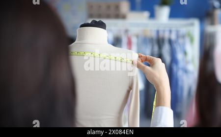 Modedesignerin Stylistin nimmt Messungen mit Zentimeter von Kleidung auf Schaufensterpuppe Stockfoto
