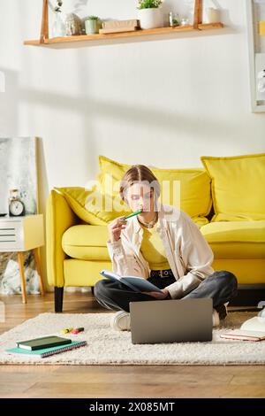 Ein Mädchen im Teenageralter, das in E-Learning eingetaucht ist, sitzt auf dem Boden, in ihrem Laptops glühen. Stockfoto