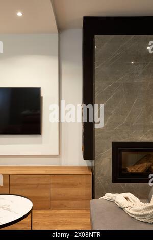 Eine gemütliche, moderne Wohnzimmerecke mit elegantem Kamin, eingebautem Fernseher und eleganten Holzmöbeln Stockfoto