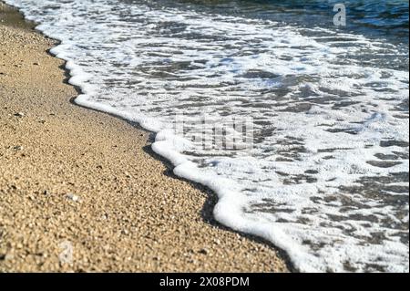 Meereswellen am Sandstrand bei Sonnenuntergang. Stockfoto
