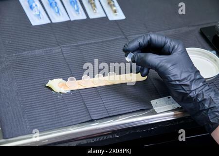 Zugeschnittene, nicht wiedererkennbare Hände von Tätowierern bereiten Tintenbehälter für eine Tätowierung vor, die Hygiene und Professionalität zum Ausdruck bringen. Stockfoto