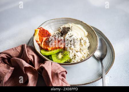 Eine nahrhafte Frühstücksschale mit cremigem Hüttenkäse, natürlichem Joghurt, Chiasamen, frischen Kiwis-Scheiben und einem saftigen Keil sizilianischer Orange Stockfoto