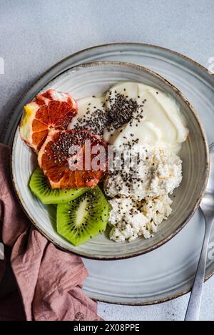 Blick von oben auf die nahrhafte Frühstücksschale mit cremigem Hüttenkäse, natürlichem Joghurt, Chiasamen, frischen Kiwi-Scheiben und einem saftigen sizilianischen Or Stockfoto