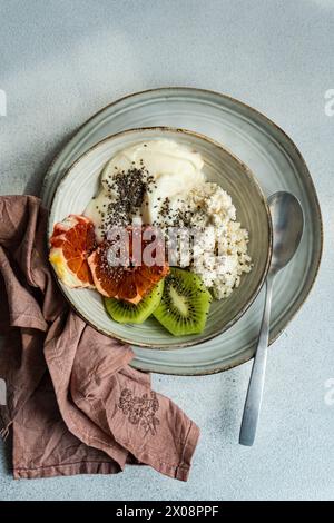 Blick von oben auf die nahrhafte Frühstücksschale mit cremigem Hüttenkäse, natürlichem Joghurt, Chiasamen, frischen Kiwi-Scheiben und einem saftigen sizilianischen Or Stockfoto