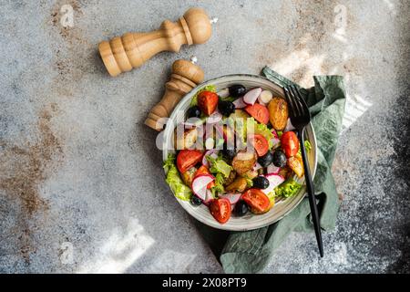 Blick von oben auf einen rustikalen mediterranen Kartoffelsalat mit Frühlingskartoffeln, schwarzen Oliven, Kirschtomaten, Frühlingszwiebeln, knusprigem Salat, und Radieschen servieren Stockfoto