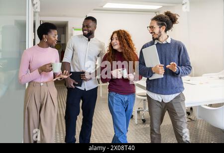 Verschiedene Gruppen lächelnder Fachleute, die während einer lockeren Büropause an einem Gespräch teilnehmen. Stockfoto