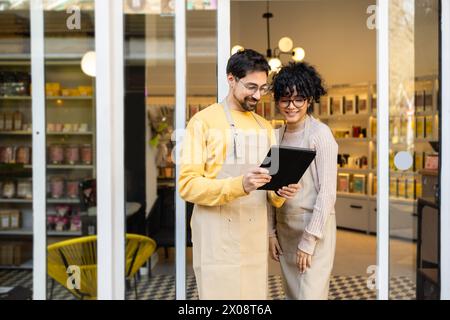 Zwei Kleinunternehmer mit digitalem Tablet am Eingang eines Boutiquen Stockfoto