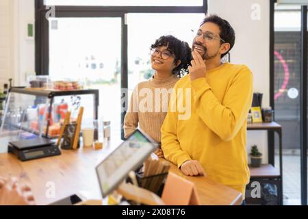 Ein fröhliches und stilvolles junges multiethnisches Paar wird in einer gemütlichen und modernen Boutique über einen Kauf nachdenken. Stockfoto