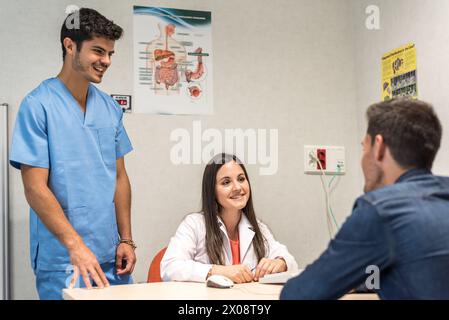 Junger Mann, der in der Arztpraxis sitzt und mit Ärzten im Krankenhaus spricht. Stockfoto