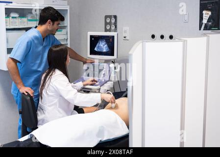 Mann und Frau Ärzte machen Ultraschalluntersuchungen bei Patienten, die im Krankenhaus liegen. Stockfoto