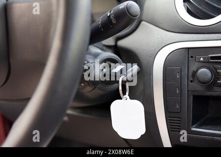 Nahaufnahme der Zündung eines Fahrzeugs mit eingeschaltetem Schlüssel und leerem Schlüsselanhänger, bereit für Branding oder Personalisierung im Fahrzeuginnenraum Stockfoto