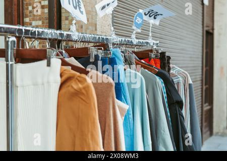 Eine Reihe von ermäßigten Modeartikeln, die auf einem Kleiderständer vor einem Geschäft ausgestellt werden, mit sichtbaren Preisschildern, die Käufer anziehen Stockfoto