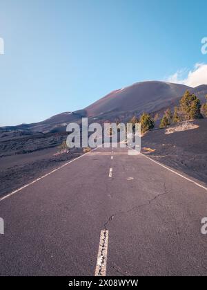 Eine einsame Straße erstreckt sich in Richtung der Vulkanlandschaft der Insel La Palma unter einem klaren blauen Himmel Stockfoto