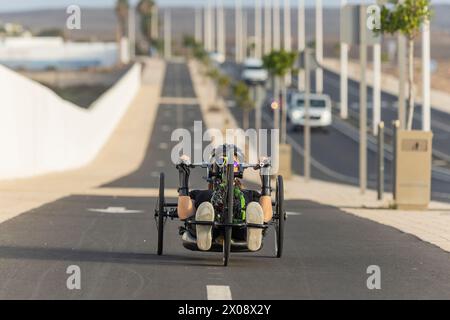 Eine weibliche, nicht erkennbare Handradrennerin mit einem Behindertentraining auf einer städtischen Straße, die Entschlossenheit und Sportlichkeit zum Ausdruck bringt. Stockfoto