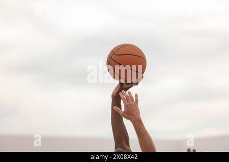 Ein Basketball, der in der Hand eines Spielers vor einem weichen Hintergrund gehalten wird, bereit für Action auf dem Platz im Freien Stockfoto