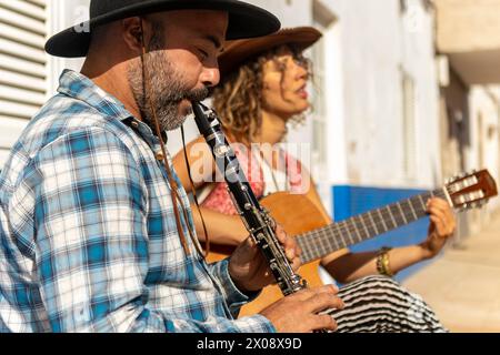 Ein Duo von Straßenmusikern tritt an einem hellen, sonnigen Tag in einer Stadtstraße mit Klarinette und Gitarre auf und teilt ihr Talent. Stockfoto
