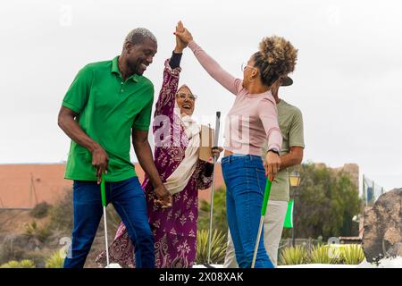 Vielfältige Gruppe von Freunden, die gerne auf einem Minigolfplatz feiern. Stockfoto