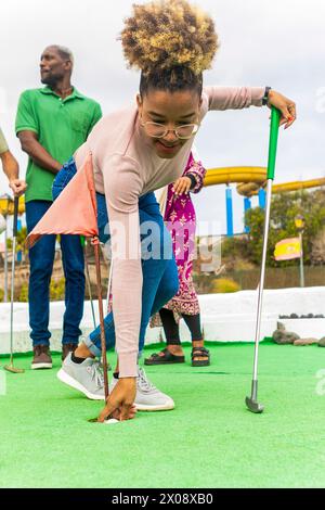 Gruppe von Freunden, die eine Minigolf-Runde auf einem lebhaften grünen Golfplatz genießen. Stockfoto