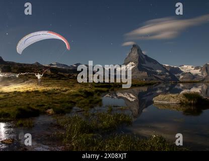 Ein Gleitschirmflieger steigt in die Luft, während sich das Matterhorn in den Gewässern des Stellisees unter einem Sternenhimmel spiegelt Stockfoto