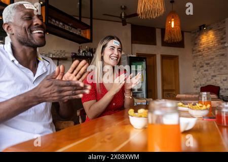 Eine Gruppe von Freunden genießt einen verspielten Moment in einer Bar, bei Getränken und Snacks auf dem Tisch, die Spaß und Lachen haben Stockfoto