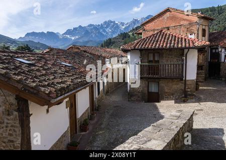 Malerische Kopfsteinpflasterstraße gesäumt von traditionellen Steinhäusern in Potes, Kantabrien, mit den malerischen Picos de Europa-Bergen in der Ferne. Stockfoto