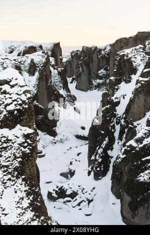 Ein Winterblick auf den Fjadrargljufur Canyon in Island, mit Schnee, der die zerklüfteten Konturen der alten Klippen unterstreicht Stockfoto