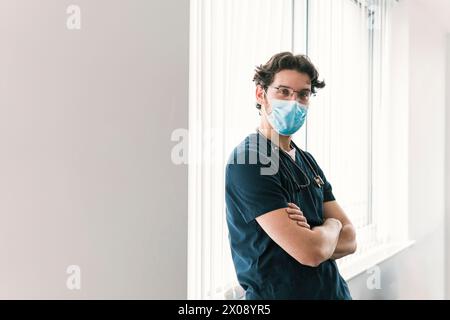 Ein wachsamer männlicher Gesundheitsexperte in Navy-Peelings trägt eine Maske, die Sicherheit in medizinischen Umgebungen verkörpert Stockfoto