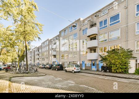 Sonniger Tag in einer ruhigen Wohnstraße, gesäumt von modernen Apartmenthäusern, geparkten Autos und Fahrrädern. Stockfoto