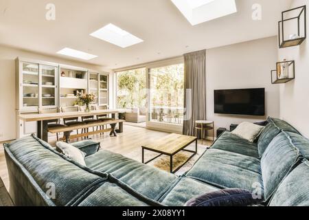 Helles und modernes Wohnzimmer mit Oberlichtern, weichem Sofa und Blick auf eine ruhige Terrasse im Freien. Stockfoto